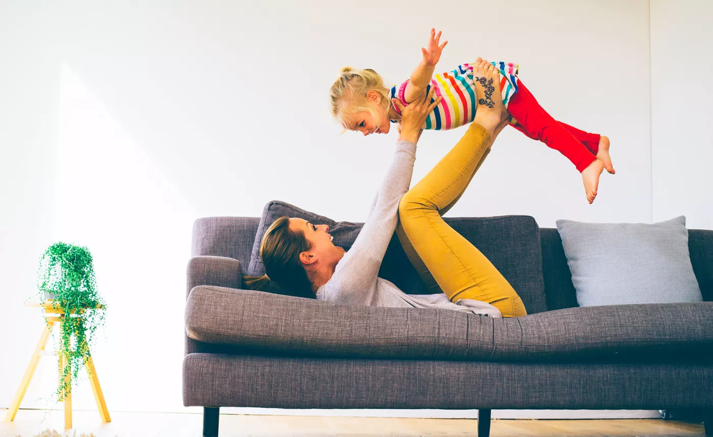  Parent laying on couch lifting child in the air
