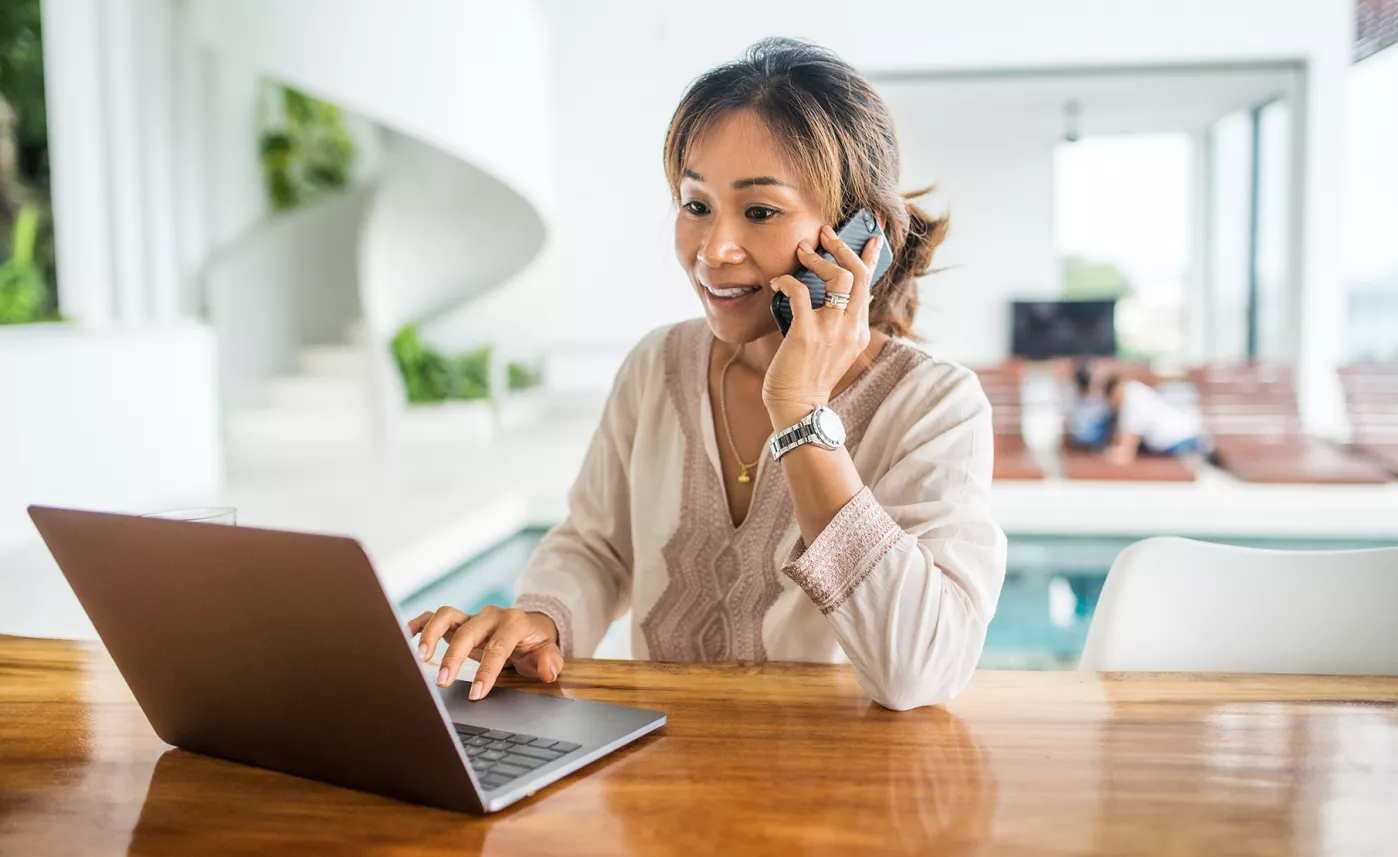  Une femme fait un appel téléphonique pendant qu’elle travaille sur son ordinateur portable.
