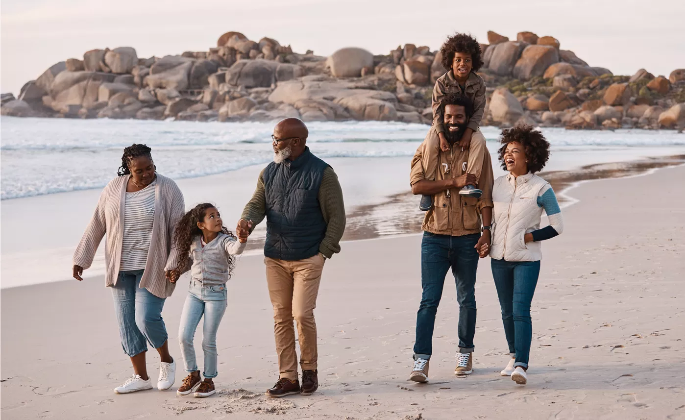  A multigenerational family walking happily along a beach
