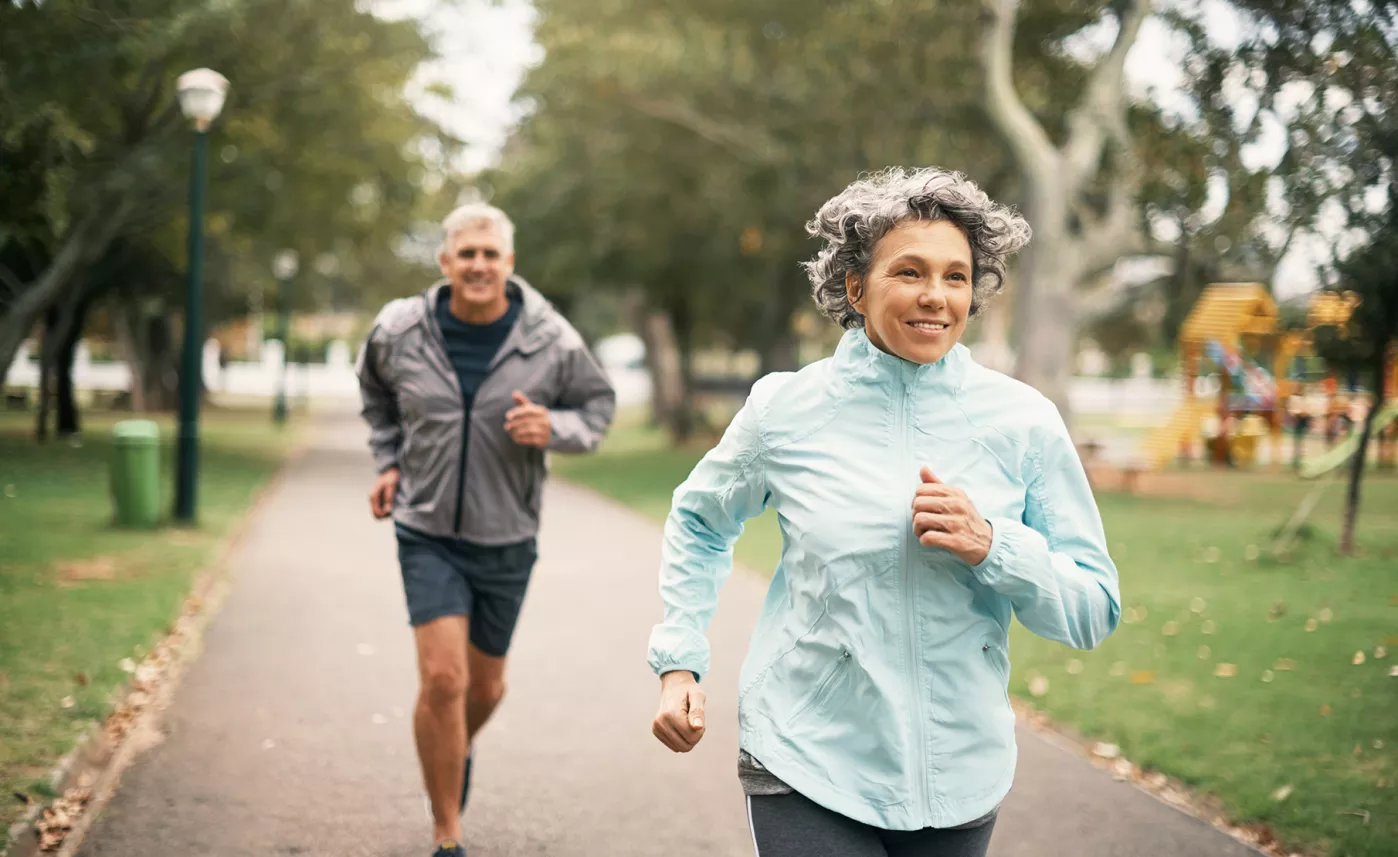  Deux personnes en santé et en âge de prendre leur retraite joggent dans un parc.
