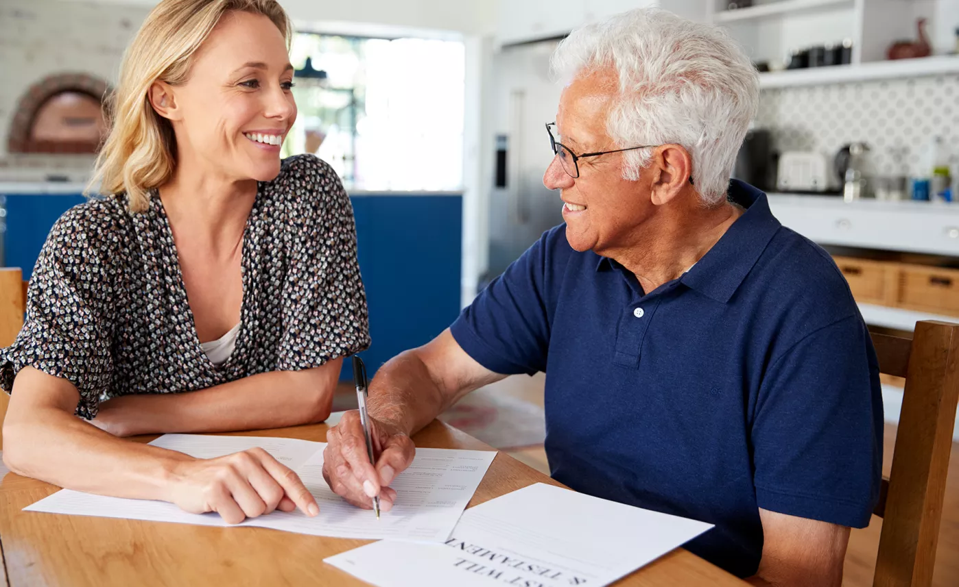  An elderly man reviews financial documents with his adult daughter.
