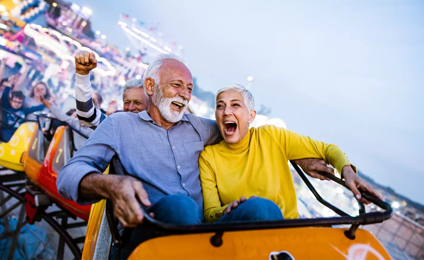  Un couple à l’âge de la retraite s’amuse dans des montagnes russes.
