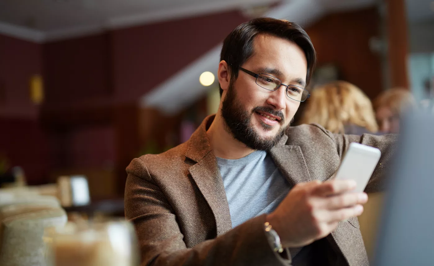  Un jeune homme regarde l’écran de son téléphone mobile pendant qu’il communique avec son conseiller financier.
