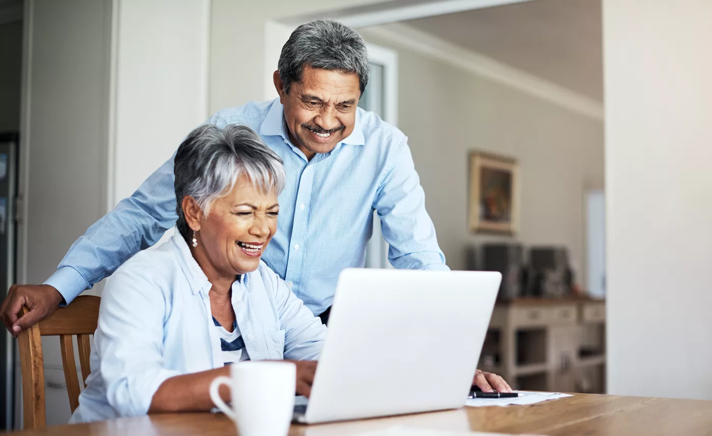  A retirement-aged couple reads information about trusts on their laptop at their kitchen table.
