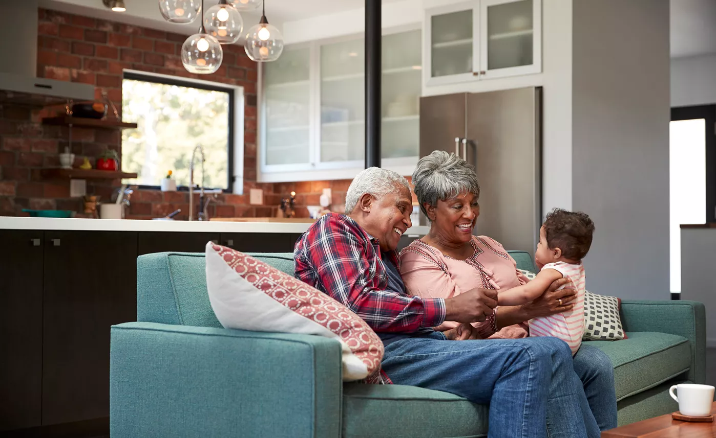  Deux grands-parents s’assoient dans leur maison avec leur petit-fils en bas âge.
