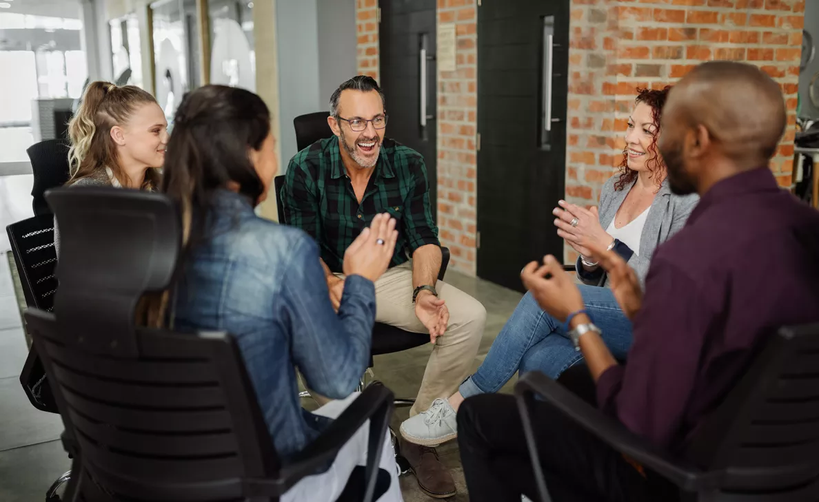  A group of adults talk in a circle in a trendy office building.
