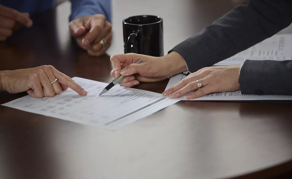  An Edward Jones analyst discusses financial reports with two clients at their office.
