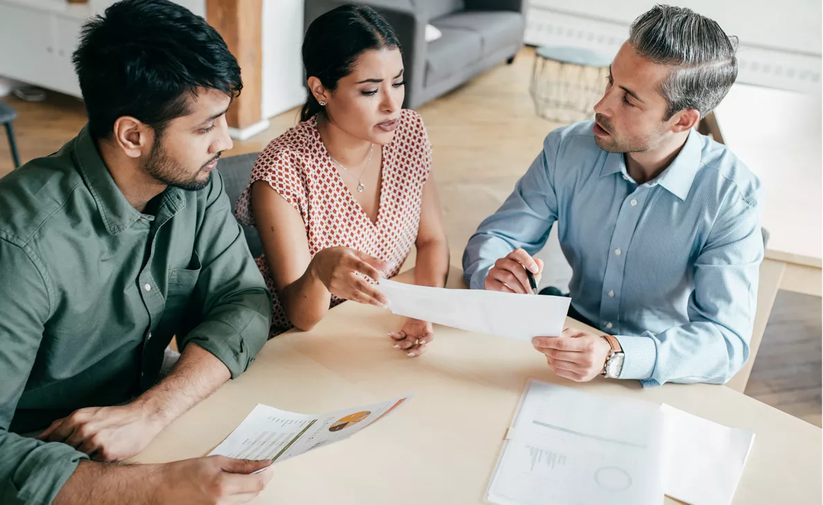 An Edward Jones advisor explains information on documents to two clients in their home.