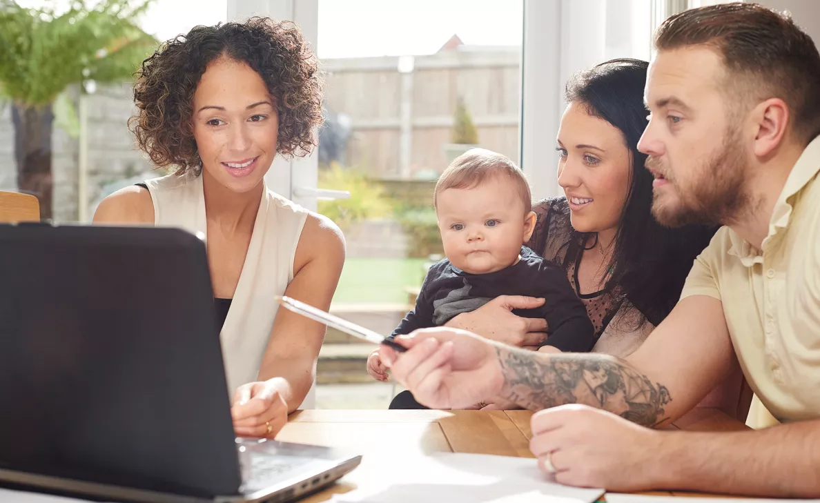Un conseiller en investissement Edward Jones présente des options d’épargne à de jeunes parents accompagnés de leur bébé.
