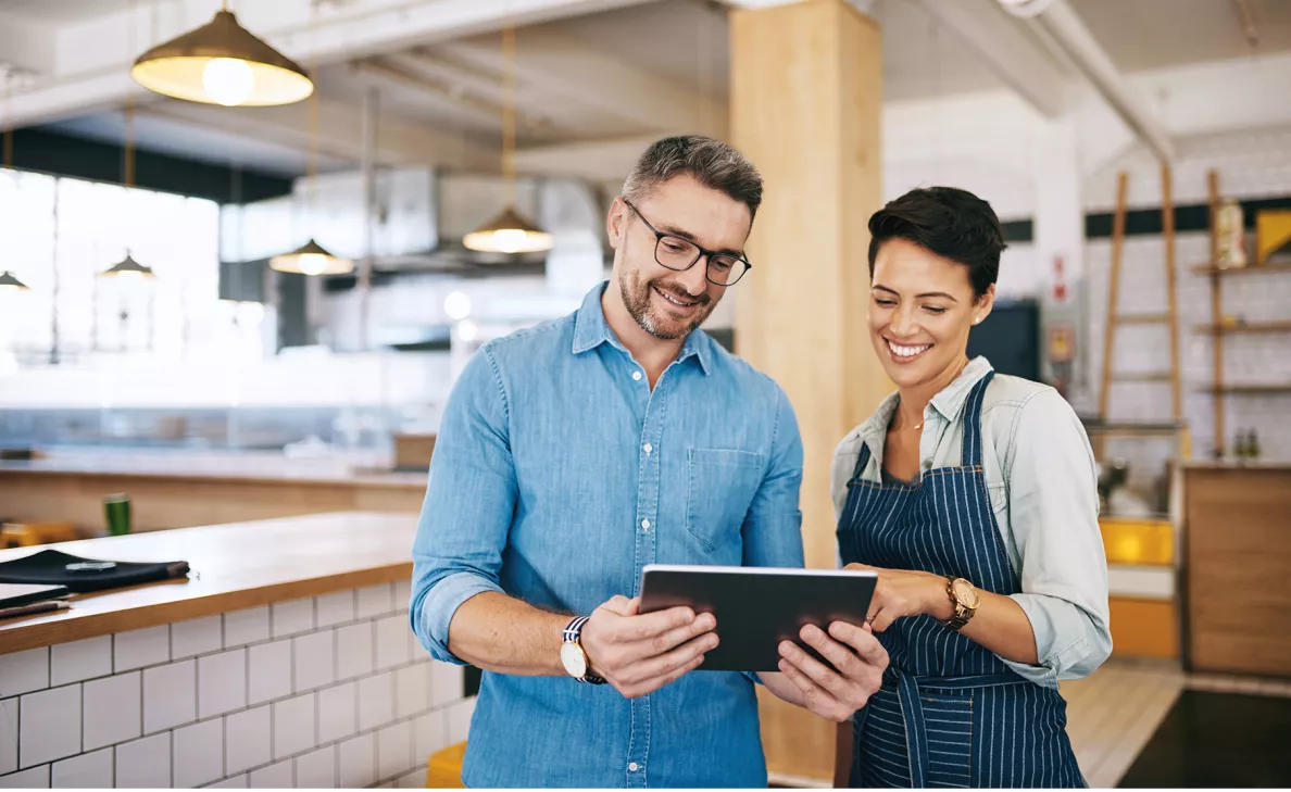 Un représentant en services financiers discute dans un café avec sa propriétaire des renseignements de compte qui sont affichés sur une tablette