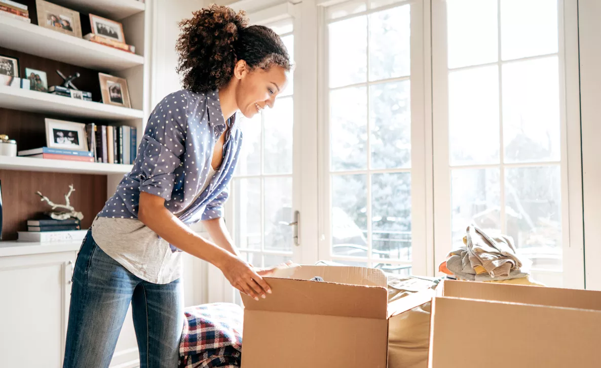  A woman unboxes her things in a new home after a recent move.
