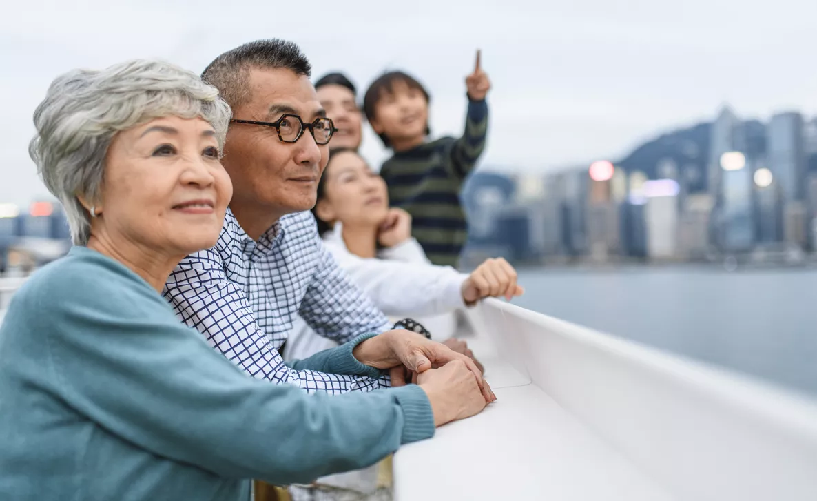  Two generations of a family looking into the distance, smiling, in front of a blurred city line in the background.
