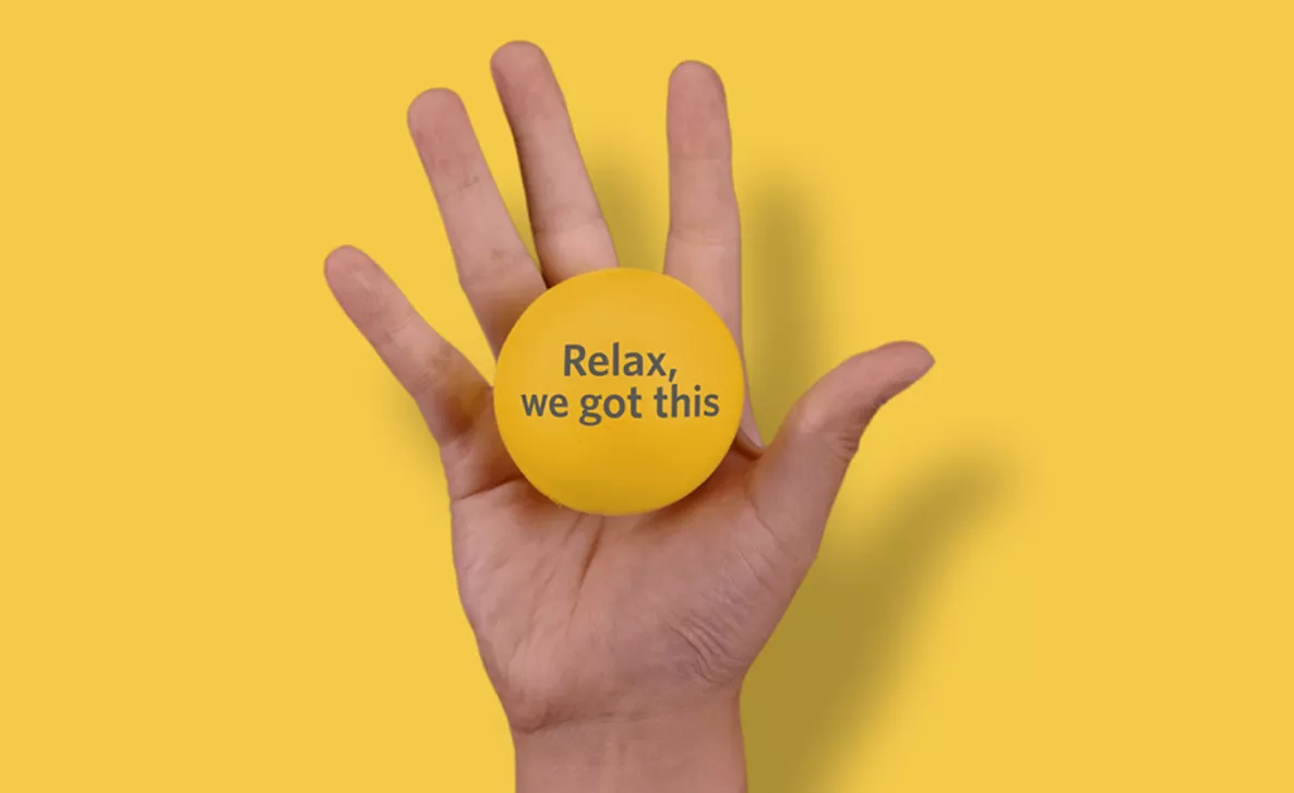  open hand holding a stress ball with the words "relax, we got this" on it
