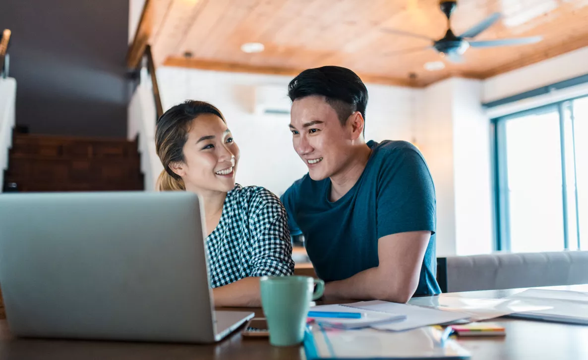  Un couple heureux regarde un ordinateur portable ensemble.
