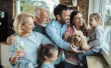 Multiple generations of a family with their dog, laughing together.