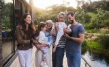 A small family laughing together outside their beautiful home