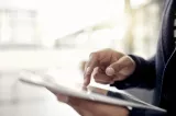 Close-up of hands holding and using a tablet device.