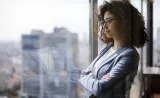 A woman confidently looks out a window on the first day of her new job.