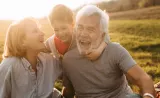 A grandson hugs his grandparents as they laugh together.