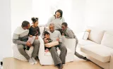Family sitting on couch with Grandfather next to little girl